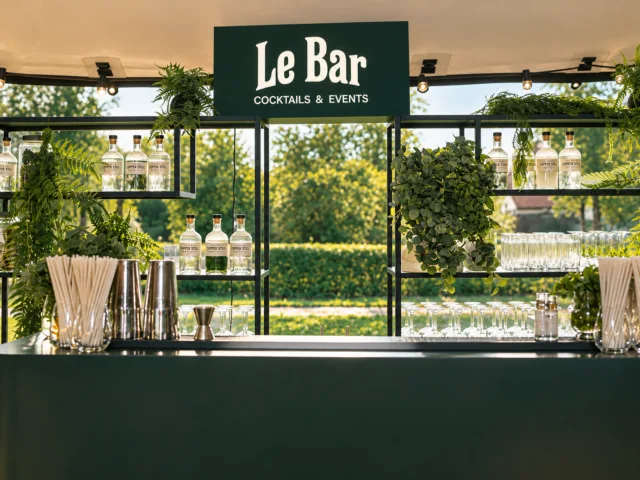 Groene Le Bar cocktailbar met verlicht logo, planten en glaswerk klaar voor een event